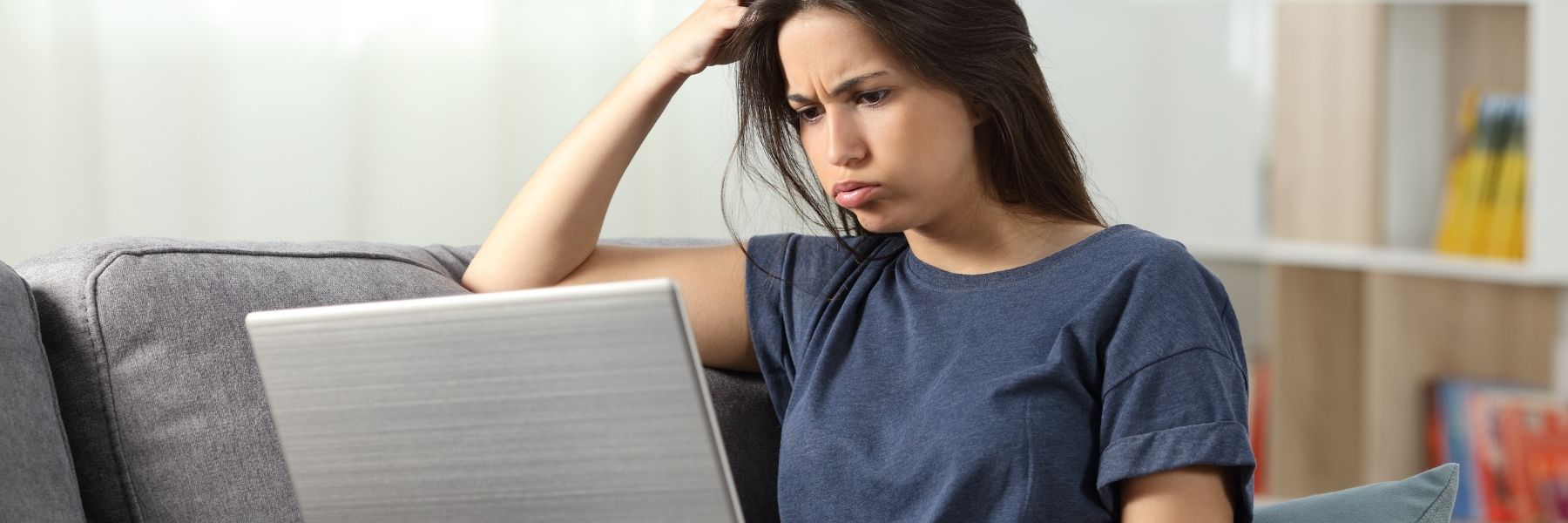 Young woman looking frustrated and working on laptop