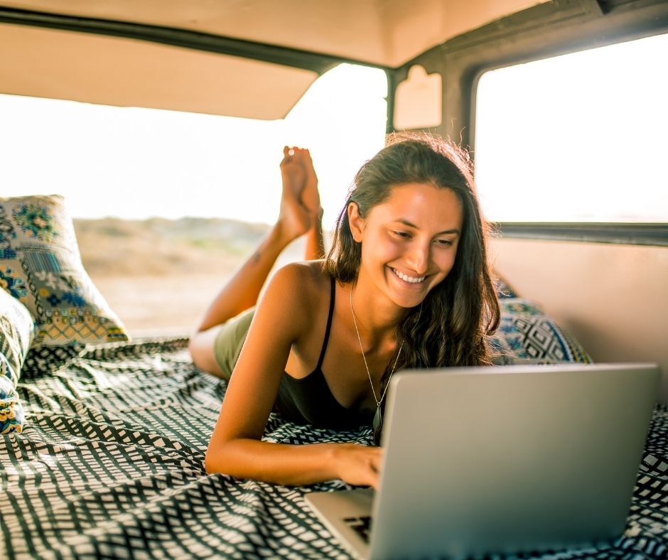 Smiling woman typing on laptop in a van