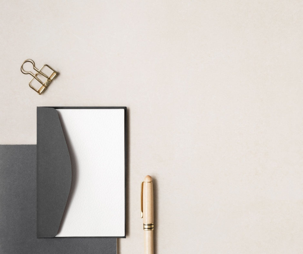 Blank notepad with a gold pen and binder clip on a beige surface, part of studio anansi's website strategy collection.