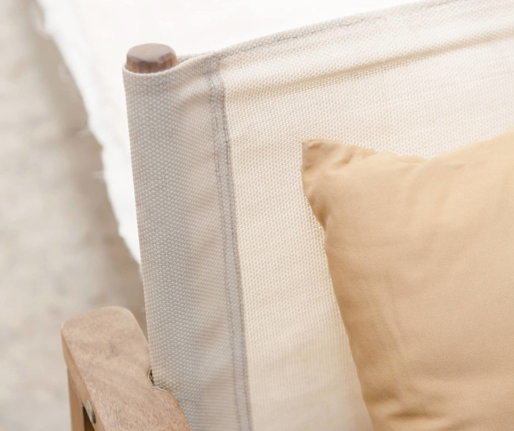 Close-up of a beige cushion on a studio anansi chair with a white mesh backrest.