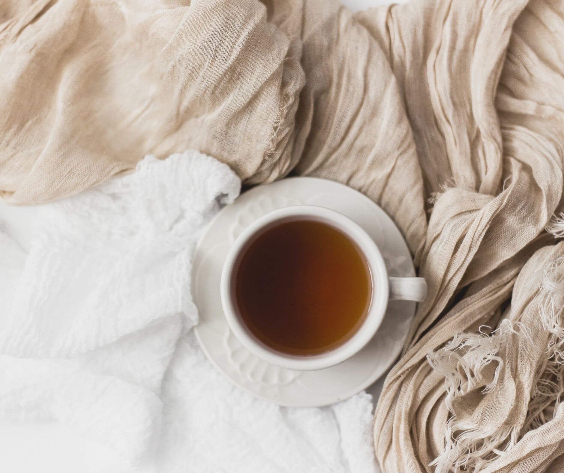 A cup of tea, featured on Elliot Olson's Portland, Oregon website strategy page, rests on a white surface with draped beige linens.